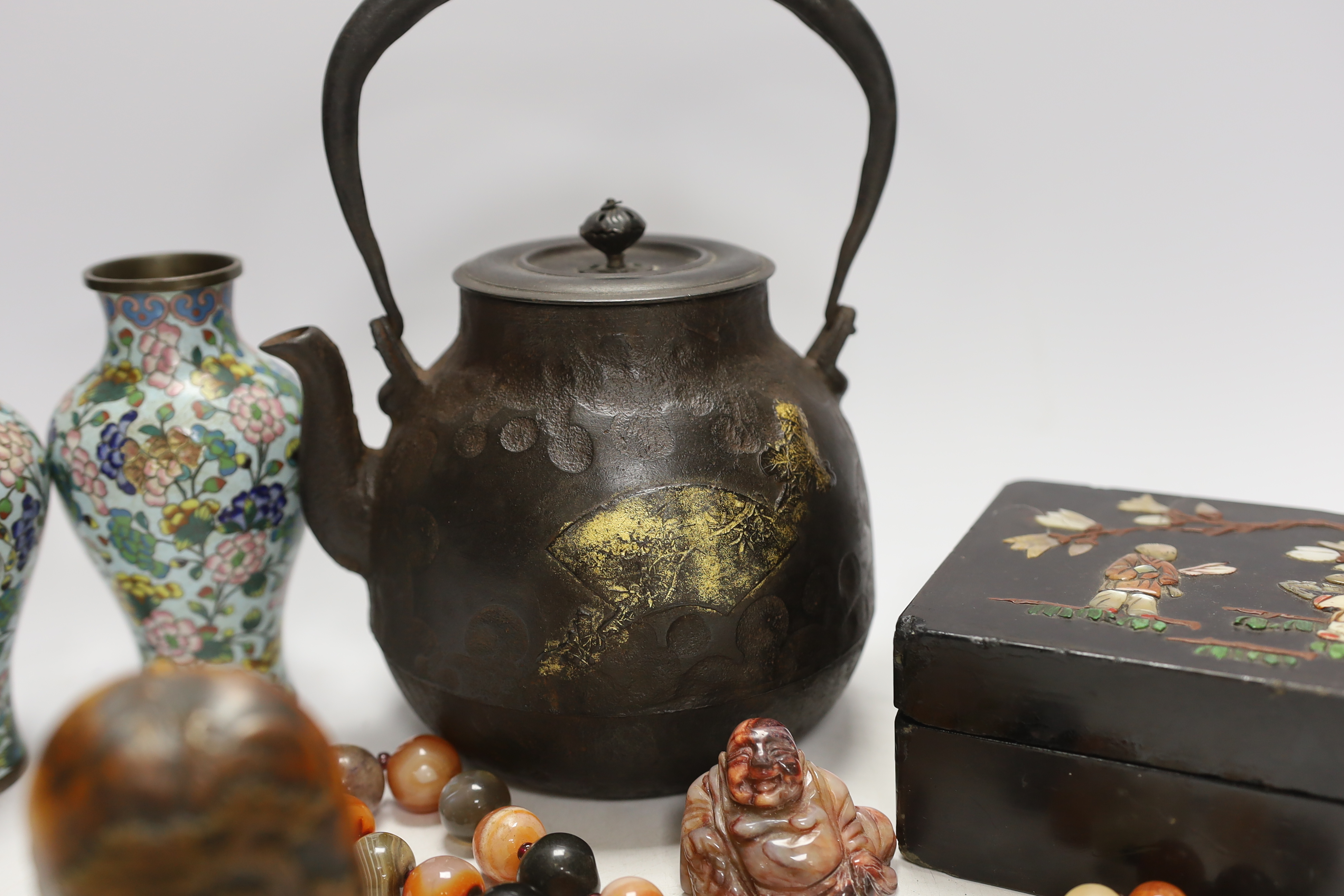 A Japanese iron tetsubin kettle with gilt decoration, a pair of Chinese cloisonné enamel vases, 12.5cm, a lacquered box with mother of pearl inlay, a carved black stone disc, 5cm diameter, a miniature ceramic pot and an